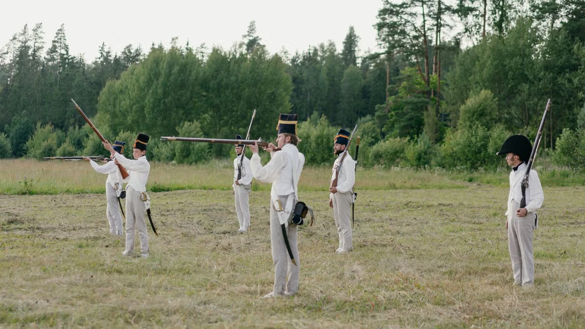 Group of soldiers practicing historical battlefield reenactment outdoors.